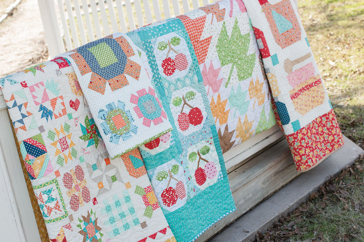Farm Girl Vintage by Lori Holt – farm sampler quilt displayed on a bench